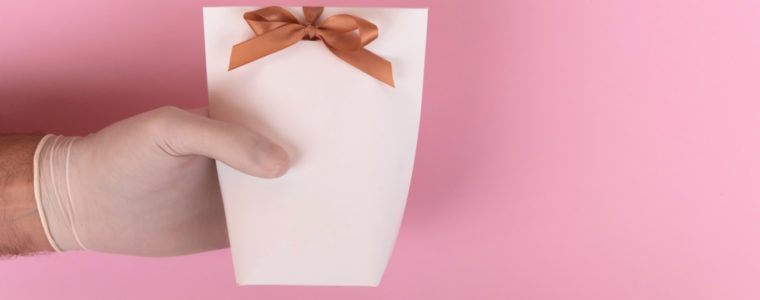 A gloved hand holding a small gift pouch with a bow on it.