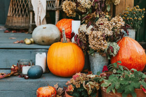 Pumpkins and Fall flowers decorate the entrance to a home.